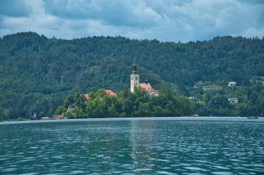 Slovenya 'da Bled Gölü, Kan Kanı Kilisesi ve Julian Alpleri' nin panoramik manzarası yemyeşil yemyeşil ormanlarla dolu