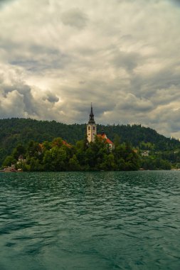 Slovenya 'da Bled Gölü, Kan Kanı Kilisesi ve Julian Alpleri' nin panoramik manzarası yemyeşil yemyeşil ormanlarla dolu