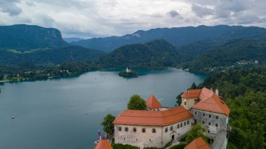  Bled Gölü (Blejsko Jezero) ile güzel Kanlı Kale 'nin (Blejski Grad) havadan panoramik görüntüsü, Maria' nın Hükmü Kilisesi ve Julian Alpleri 'nin üzerine bulutlu bir gökyüzü.