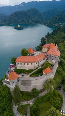  Bled Gölü (Blejsko Jezero) ile güzel Kanlı Kale 'nin (Blejski Grad) havadan panoramik görüntüsü, Maria' nın Hükmü Kilisesi ve Julian Alpleri 'nin üzerine bulutlu bir gökyüzü.