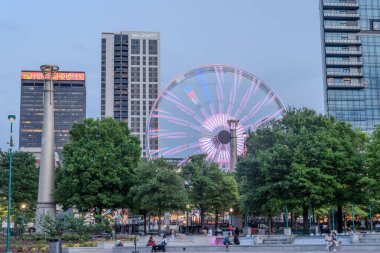 Atlanta, ABD: 19 Nisan 2025: Atlanta şehir merkezinde günbatımında gökyüzü, binalar, dönme dolap ve turistler Atlanta şehir merkezinde serin bir bahar haftasonunun keyfini çıkarıyorlar
