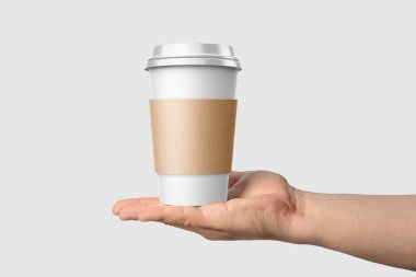 Paper coffee cup with sleeve in a hand mockup template, isolated on light grey background. High resolution. clipart