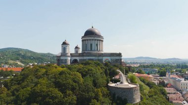 Breathtaking drone view of the grand Esztergom Basilica perched on a scenic mountain top, overlooking the historic city and picturesque landscape