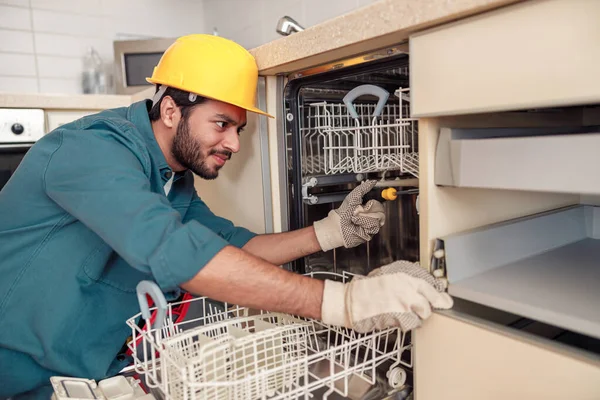 Service man repairing dishwasher in modern kitchen. Maintenance and household assistance concept