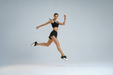 Athletic active woman jumping on studio background. Dynamic movement