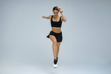 Athletic active woman wearing sportswear jumping on studio background. Dynamic movement