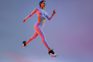 Athletic active woman jumping on studio background. Dynamic movement