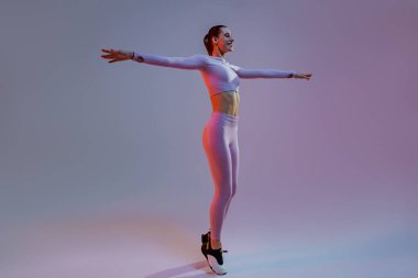 Happy woman wearing sportswear stand with raised up arms on studio background. High quality photo