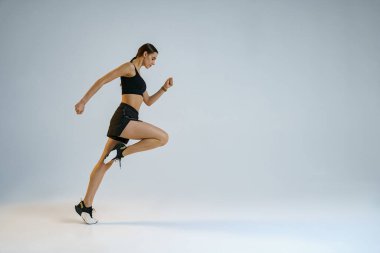 Athletic active woman running on studio background. Dynamic movement