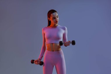 Woman doing exercises with dumbbells on studio background . Sport and healthy lifestyle