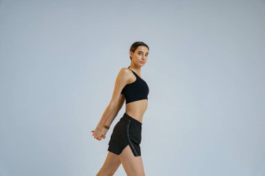 Sporty woman doing warm-up before training session in gym on studio background. High quality photo