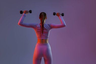 Woman doing exercises with dumbbells on studio background . Sport and healthy lifestyle
