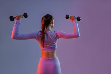 Woman doing exercises with dumbbells on studio background . Sport and healthy lifestyle