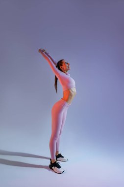 Sporty woman doing warm-up before training session in gym on studio background. High quality photo