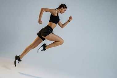 Athletic active woman jumping on studio background. Dynamic movement