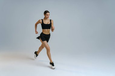 Athletic active woman jumping on studio background. Dynamic movement