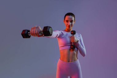 Woman doing exercises with dumbbells on studio background . Sport and healthy lifestyle