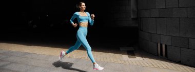 Güzel formda genç bir bayan koşucu dışarıda koşuyor.