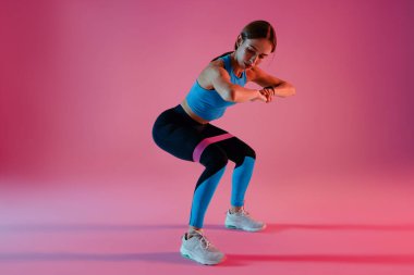 Kadın stüdyo arka planında direniş bandıyla fitness egzersizleri yapıyor. Yüksek kalite fotoğraf
