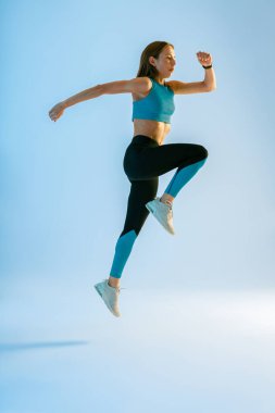 Stüdyonun arka planına atlayan atletik aktif fitness kadını. Dinamik hareket. Yüksek kalite fotoğraf