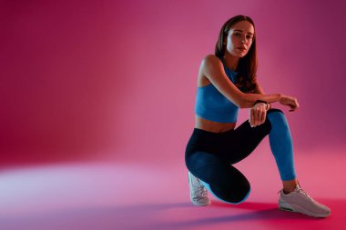 Spor kıyafetleri giymiş, stüdyo arkasında poz veren güzel bir fitness kadını. Yüksek kalite fotoğraf