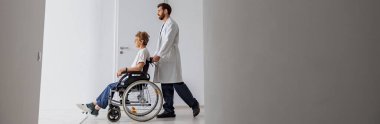 Klinikte tekerlekli sandalyeli hasta taşıyan profesyonel bir erkek doktor. Yüksek kalite fotoğraf