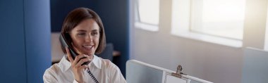 Busy woman worker talk phone with client sit on her workplace in office. Blurred background