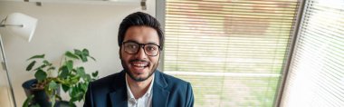Takım elbiseli gülümseyen Hintli işadamı ev ofisinden proje üzerinde çalışıyor. Serbest konsept
