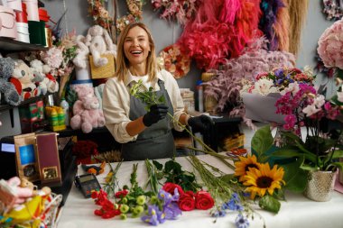 Kadın dekoratör masada güzel bir buket yapıyor. Hayat tarzı çiçek dükkanı