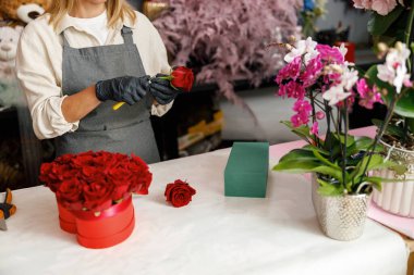 Kadın dekoratör masada güzel bir kompozisyon oluşturuyor. Hayat tarzı çiçek dükkanı