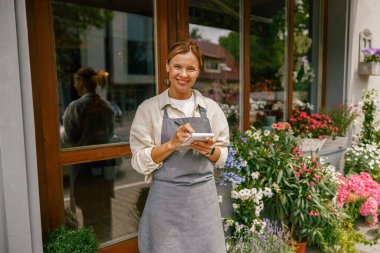 Çiçekçi kadın siparişleri ve müşteri bilgilerini çiçekçide deftere yazıyor. Yüksek kalite fotoğraf