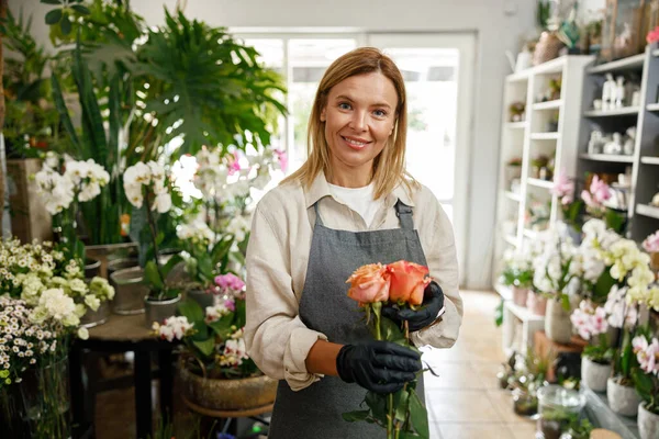 stock image Woman florist flower shop owner hold roses on floral background. High quality photo