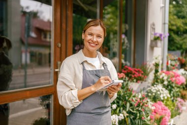 Çiçekçi kadın siparişleri ve müşteri bilgilerini çiçekçide deftere yazıyor. Yüksek kalite fotoğraf