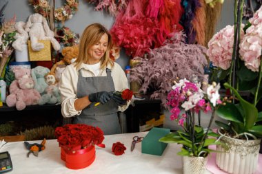 Kadın dekoratör masada güzel bir buket yapıyor. Hayat tarzı çiçek dükkanı