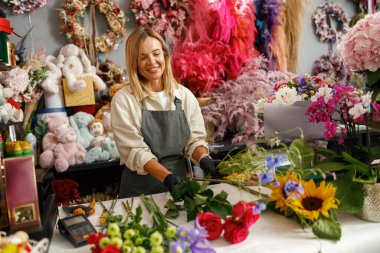 Kadın dekoratör masada güzel bir buket yapıyor. Hayat tarzı çiçek dükkanı