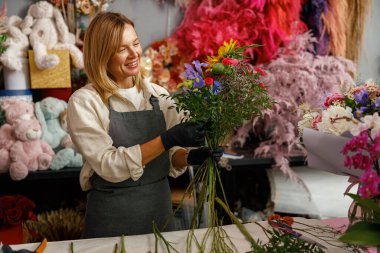 Kadın dekoratör masada güzel bir buket yapıyor. Hayat tarzı çiçek dükkanı