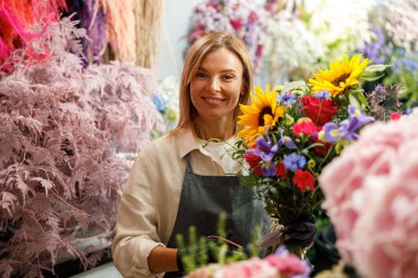 Kadın dekoratör masada güzel bir buket yapıyor. Hayat tarzı çiçek dükkanı
