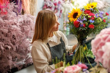 Kadın dekoratör masada güzel bir buket yapıyor. Hayat tarzı çiçek dükkanı
