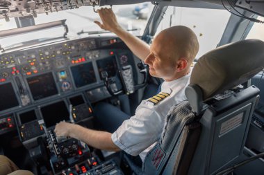 Profesyonel pilotun, bir uçak kabininde kalkışa hazır bir şekilde oturduğu yüksek açılı görüntüsü. Uçak, uçak mürettebatı, işgal konsepti
