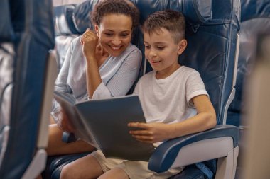 Evlat, uçakta elinde bir kitap tutan ve uçuş sırasında annesiyle birlikte gözden geçiren bir çocuk. Kabin ekibi uçakta ailesine hizmet veriyor. Havayolu taşımacılığı ve turizm kavramı