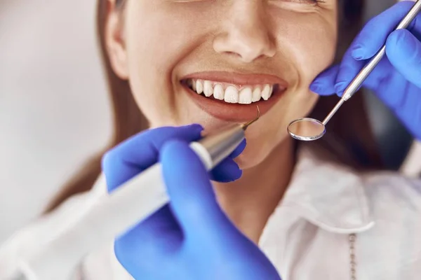 Kendine güvenen doktor modern diş dolabında ultrasonik diş taşı temizliği yapıyor.