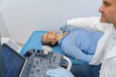 Yetişkin bir kadın doktor muayenehanesinde tiroit muayenesi yaptırıyor. Sağlık hizmetleri kavramı