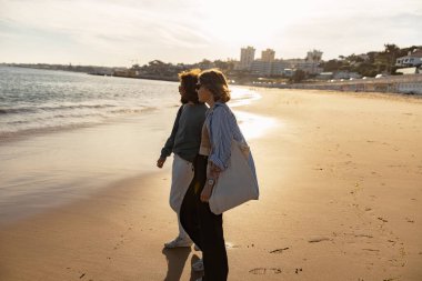 Aşık mutlu çift güneşli sahilde el ele yürür. Yüksek kalite fotoğraf
