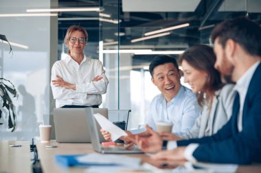 Ofisteki iş arkadaşlarıyla iş görüşmesinde gözlük takan kendine güvenen bir iş kadını. 