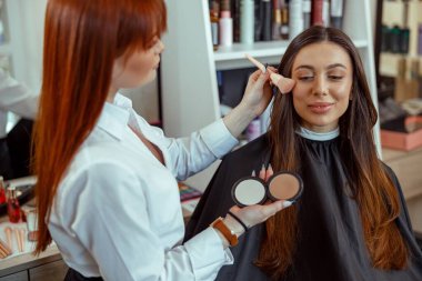 Profesyonel makyöz fırçayla bronzlaştırıcı sürüyor. Güzellik salonu hizmetleri