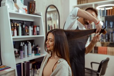 Kadın saçı keserken elinde tarak tutan profesyonel bir kuaför. Saç bakımı, güzellik.