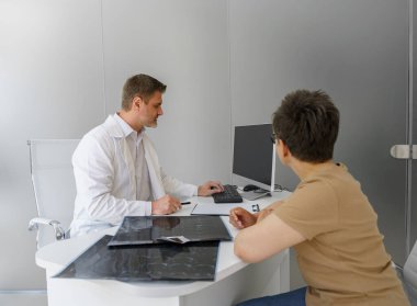 Hastanedeki hasta kadın hastaların ultrason muayenesi sonuçlarını açıklayan erkek doktor.