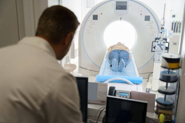 Radyoloji uzmanı MRI ya da CT taramasını hasta işlemleri ile kontrol ediyor. Yüksek Teknoloji Tıbbi Ekipmanı