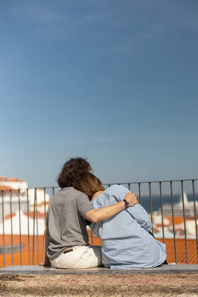 Tourist couple in love hugging while sitting on old city view background. High quality photo