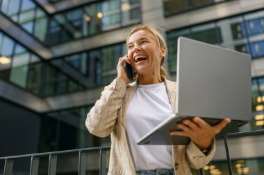 Businesswoman talking with client and work on laptop outside of office. Distance work concept